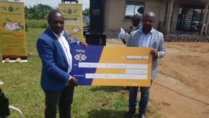 Inputi company director,Mr. David Lukwago (right) giving ugx24 million contribution to Farmers' Parliament in Gomba-recived by Robert Kabatereine (in blue coat).